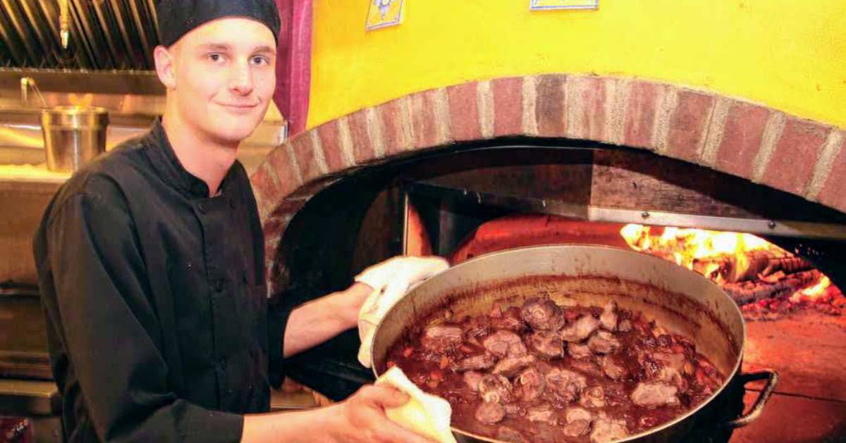 man with large pot of food