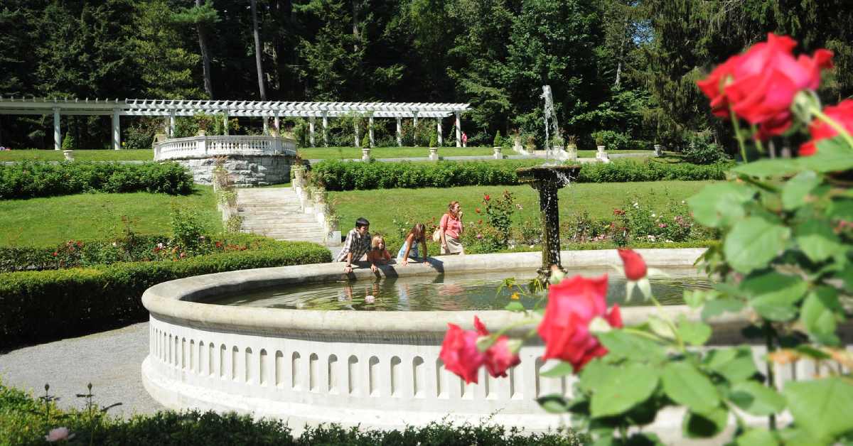 a woman and three kids stand at edge of fountain