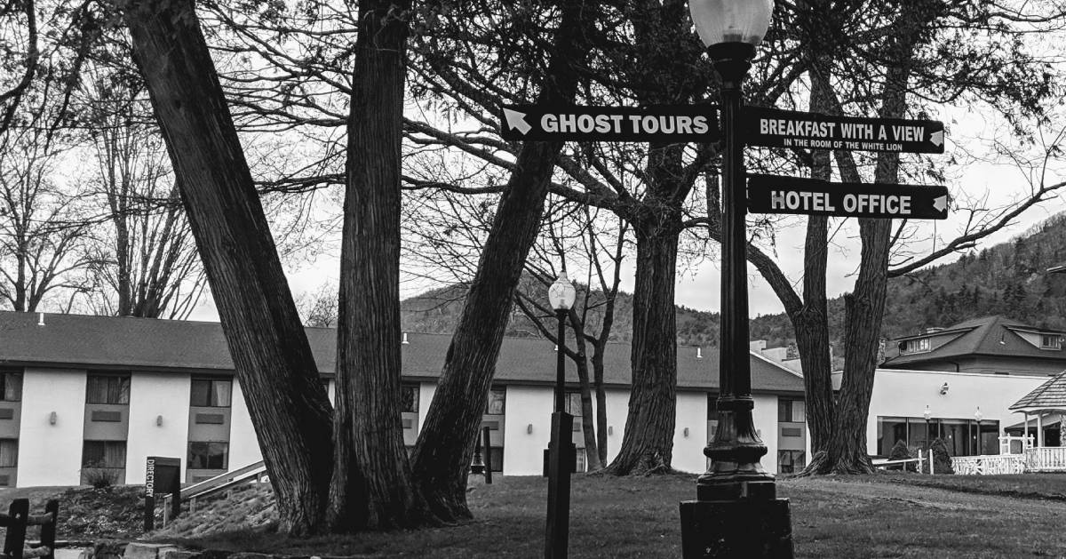 black and white photo of Ghost Tours sign, other signs, buildings