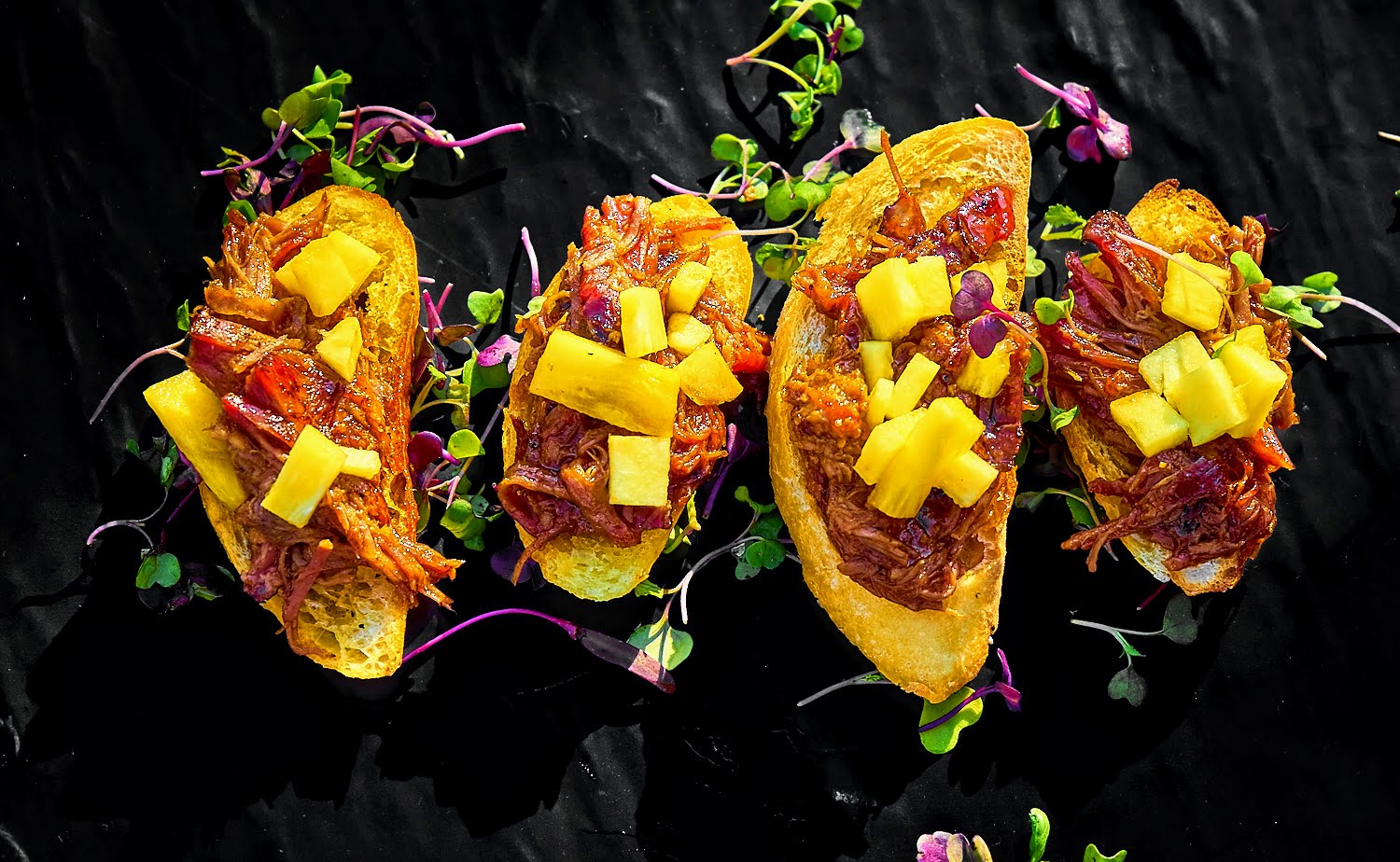 four pieces of bread with meat and fruit on them