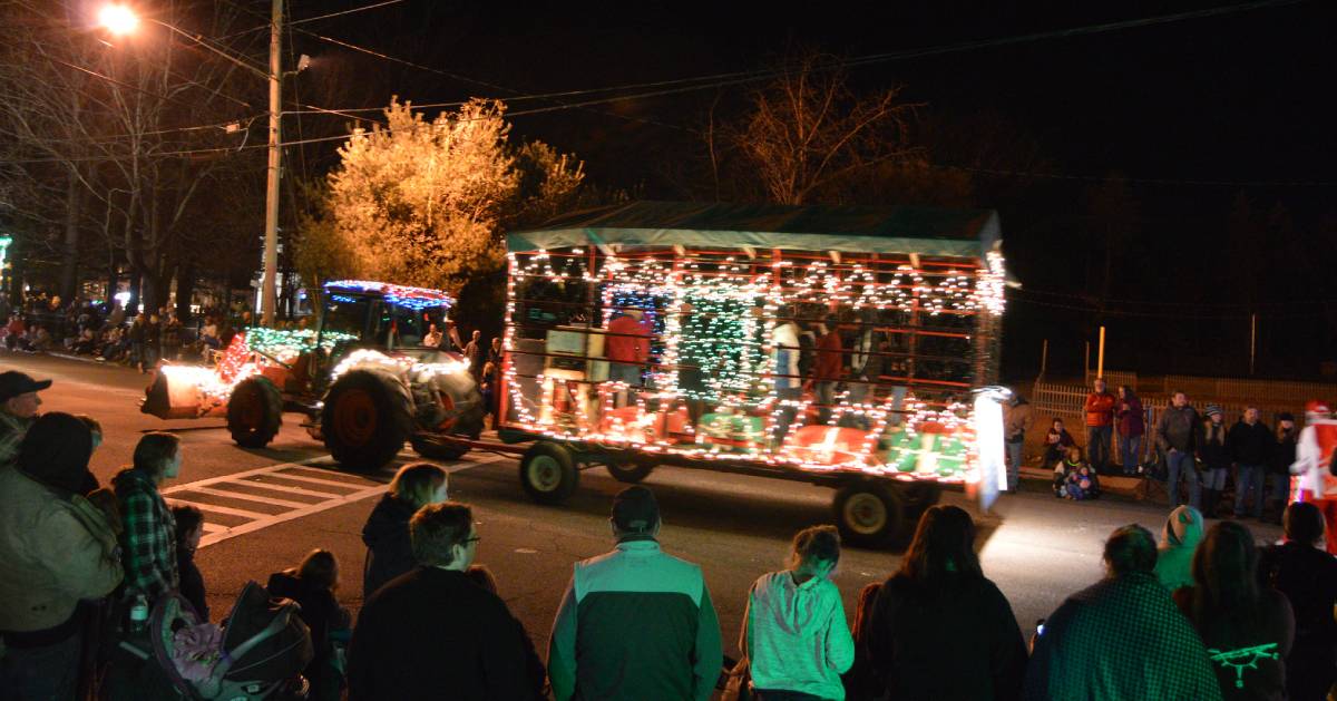 lighted tractor parade with people watching