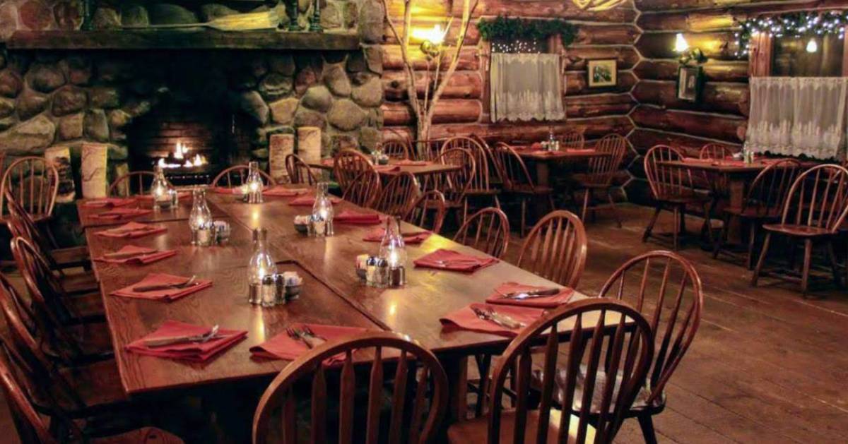 rustic dining room with tables and a stone fireplace