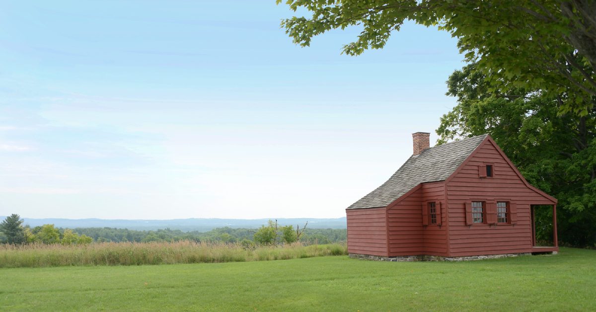 a small red house in a field overlooking the valley