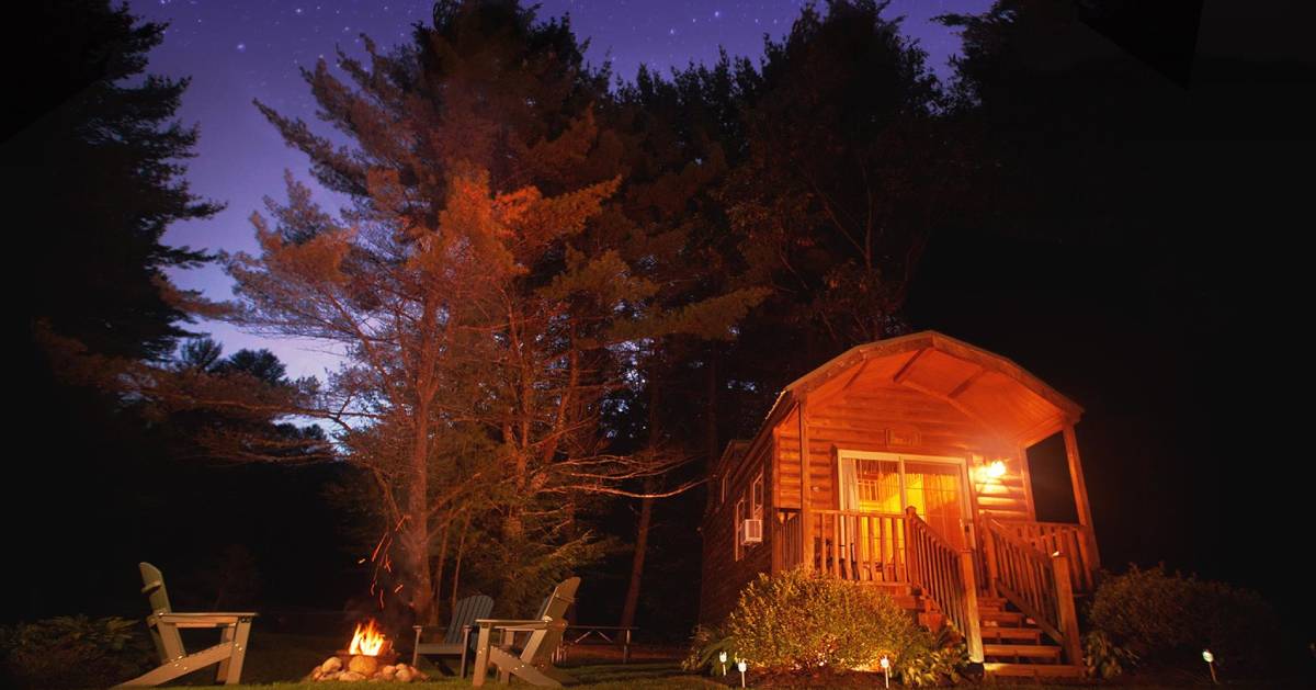 small cabin and fire in the woods at night