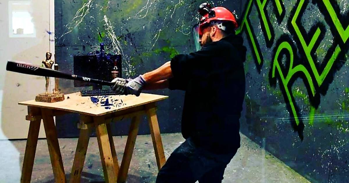 man swinging bat at a computer in a room