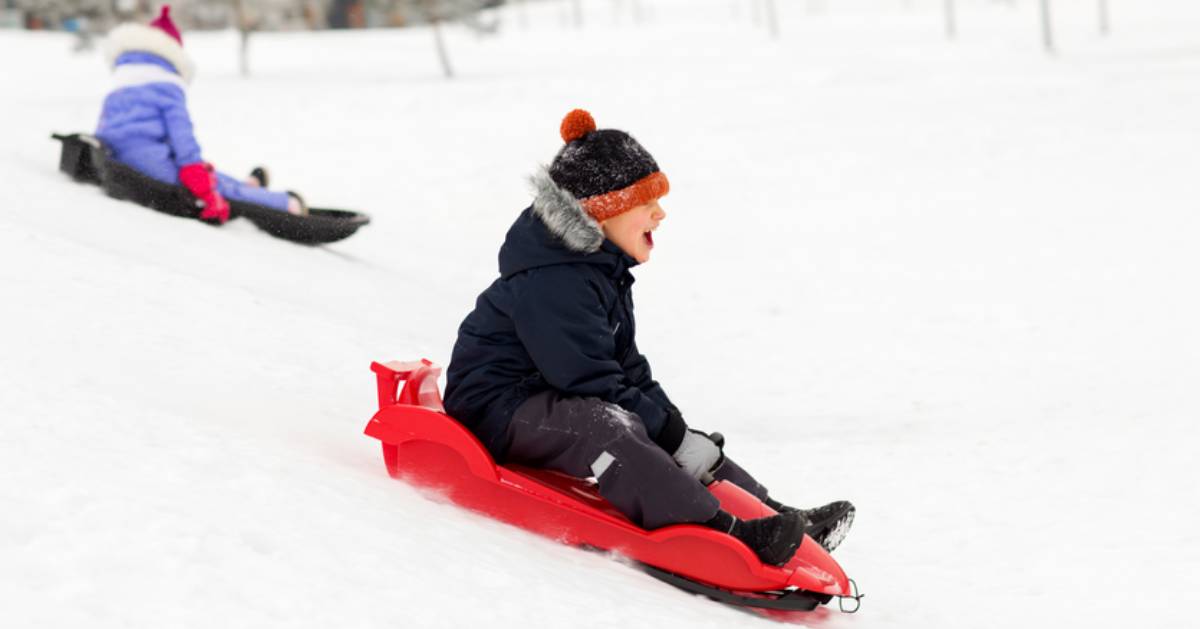kids sliding down a snowy hill