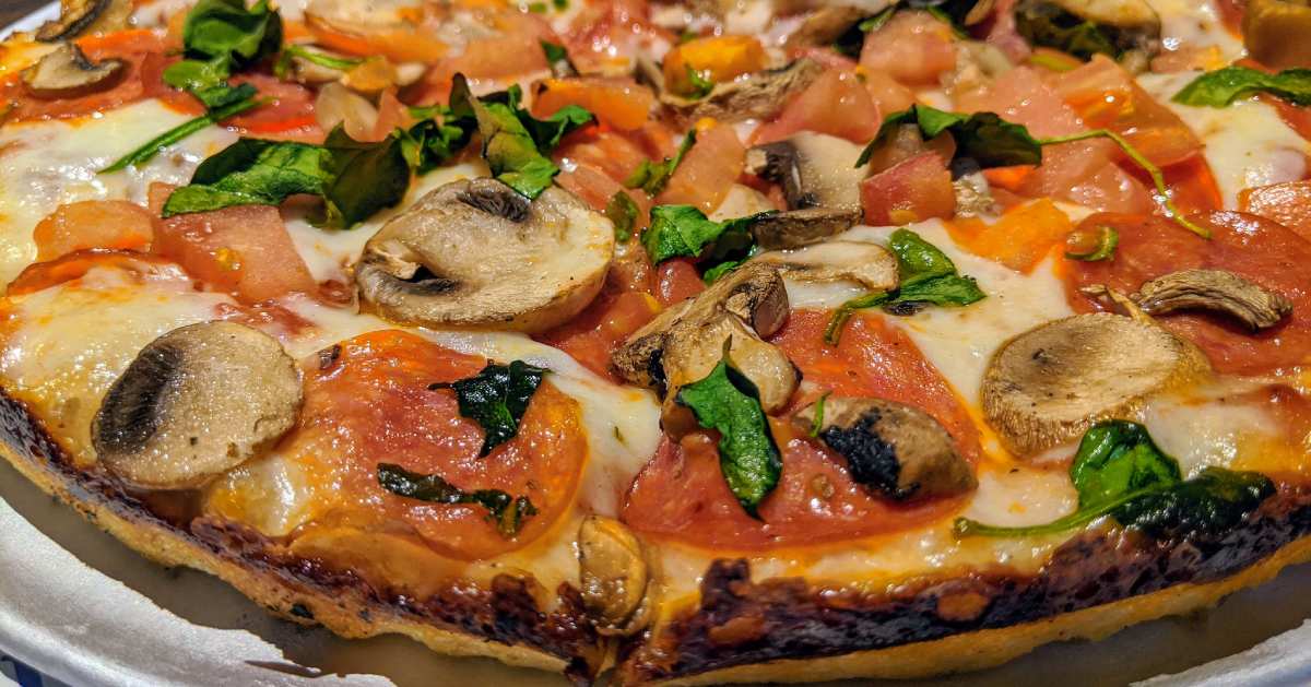 view of veggie pizza with tomatoes, basil, and mushrooms