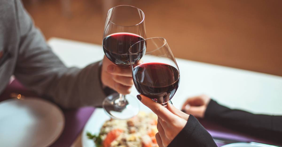 two people holding wine glasses at dinner