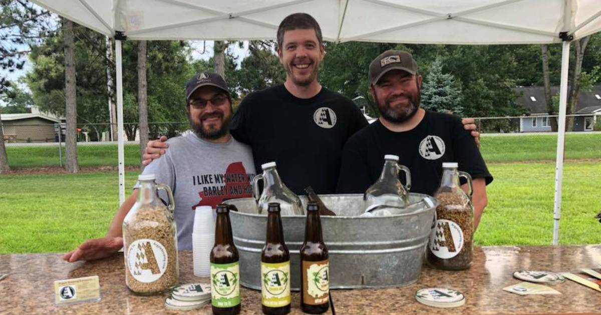 three people near beer bottles under a tent