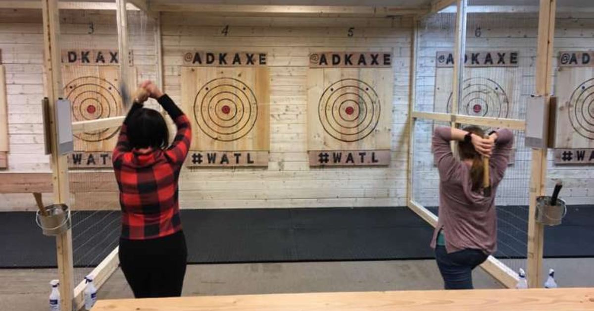 two women throwing axes at a wall
