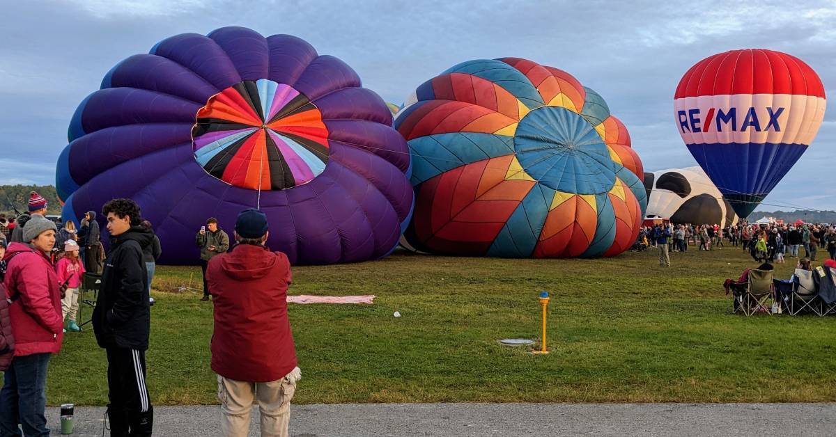 people at balloon festival, two balloons are about to go up