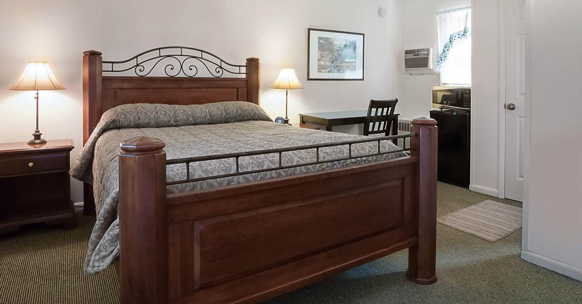 bedroom with a large bed, two cabinets with lamps on top, and a painting on one wall