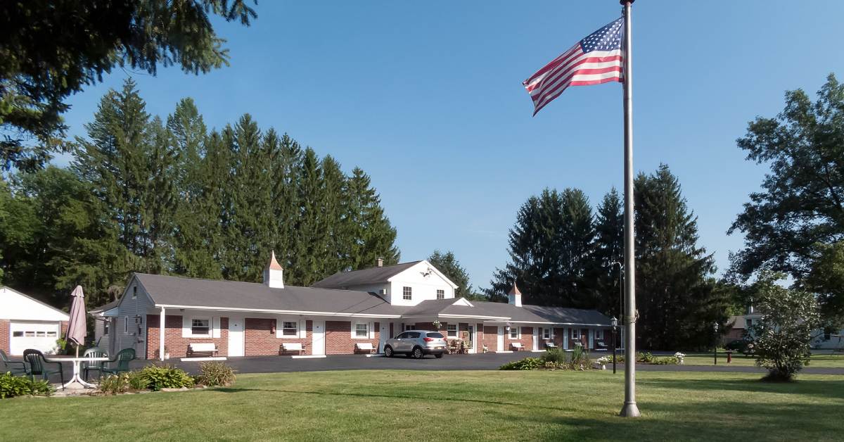 motel building on a sunny day with an American flag on a flagpole nearby