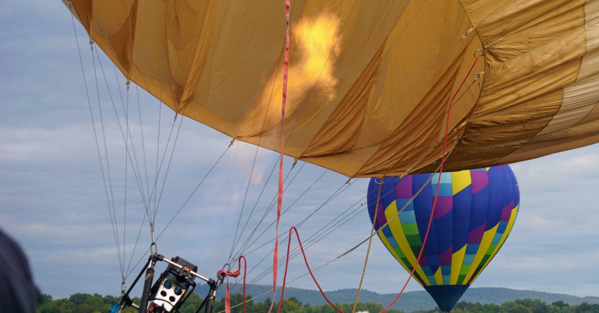 fire going up into a hot air balloon, another hot air balloon in the background