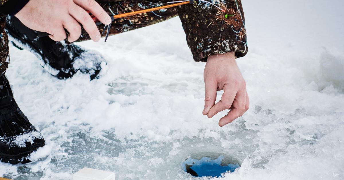 person ice fishing with pole