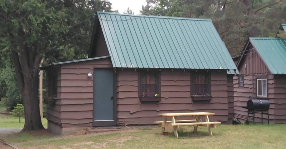 side view of a brown cabin with a picnic table and grill nearby