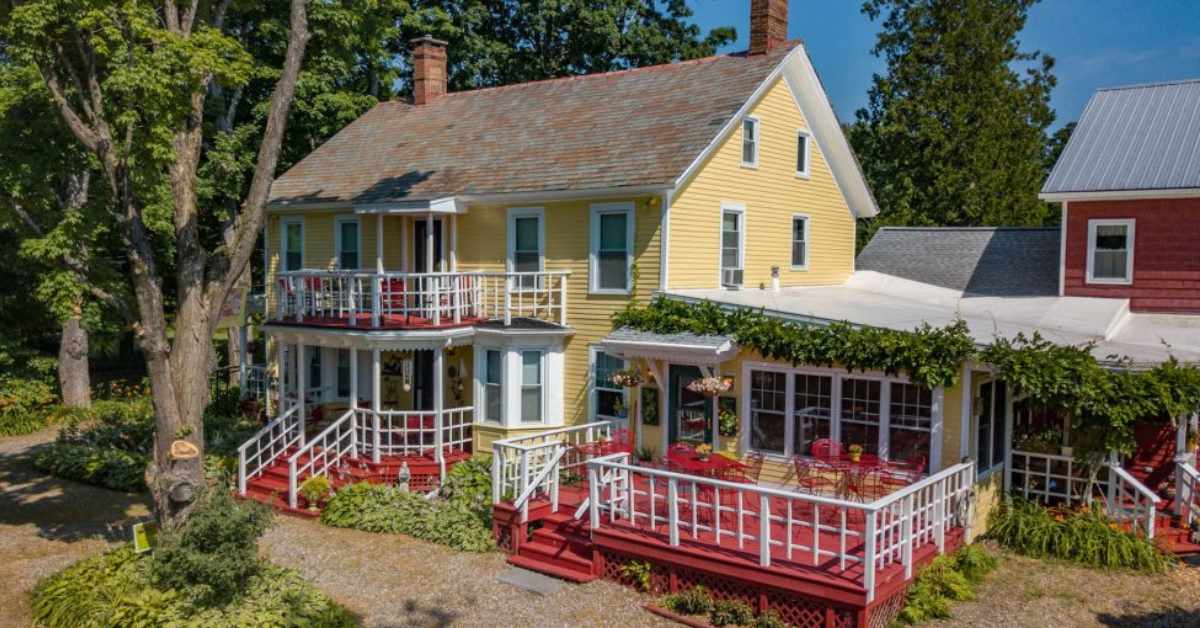 exterior of a yellow farmhouse with a deck and outdoor seating