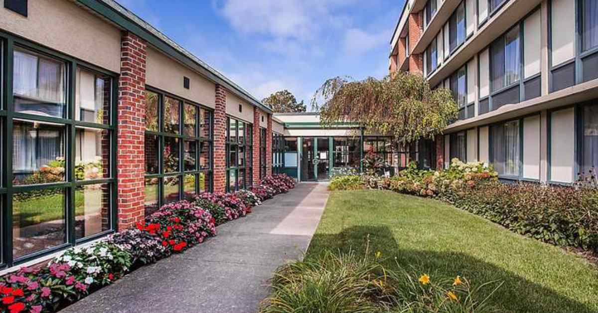 a paved path alongside flowers and a hotel building