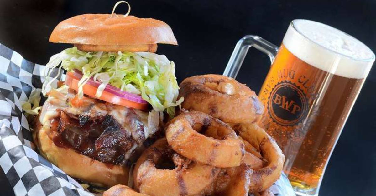 beer, onion rings, and a burger i front of a black background