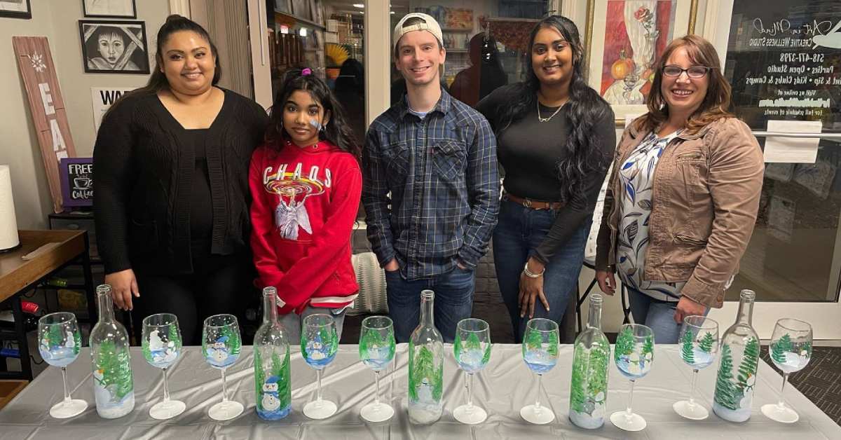 people at a paint and sip class in front of glass they painted