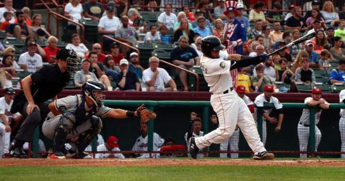 baseball player swinging the bat in front of an awestruck crowd