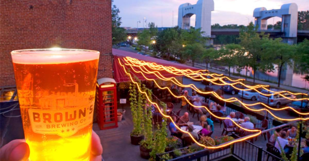 person holding a beer glass with view of patio nearby