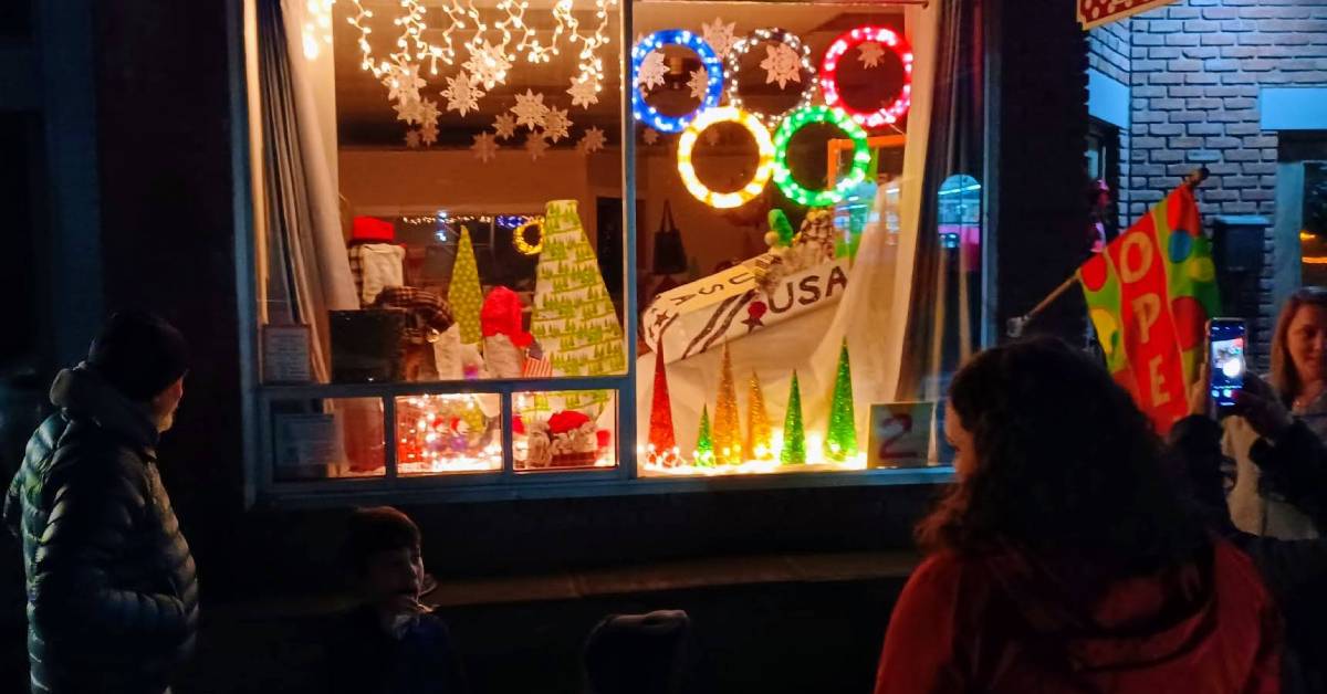 people stand around looking at holiday decorated window display