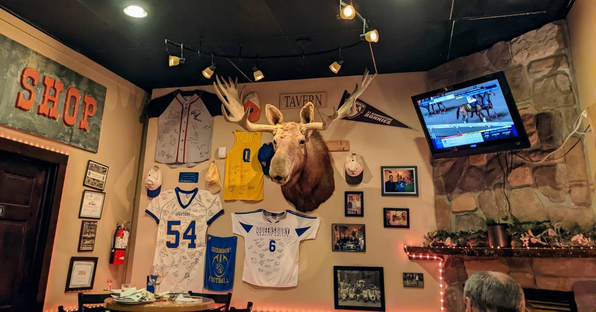 moose head hanging on wall in restaurant, tv over fireplace