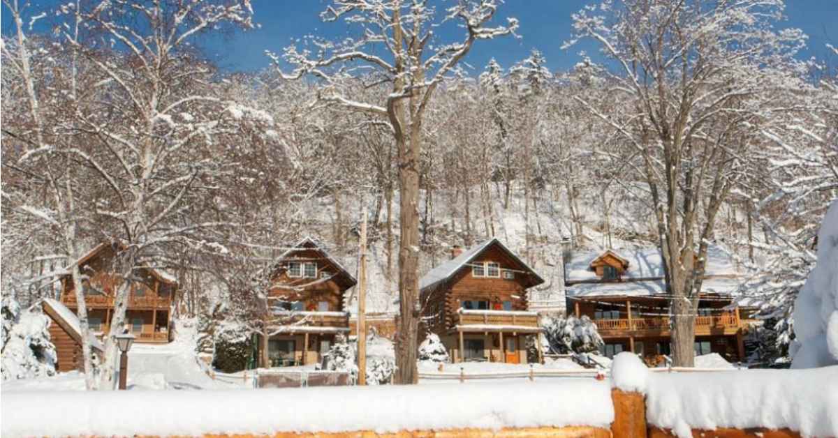 wooden cabins with snow on the ground around them