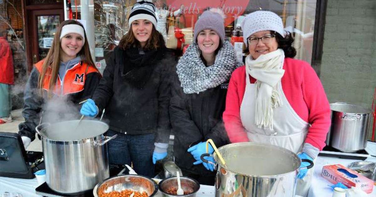 four women smiling in front of pots of chowder