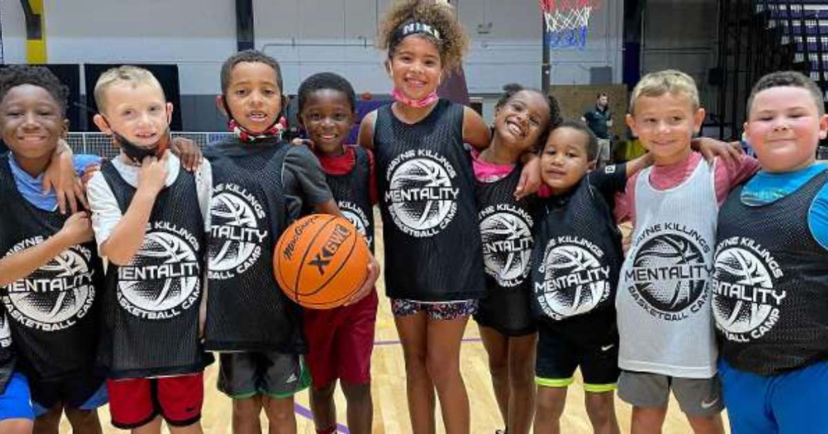 kids smiling holding a basketball with jerseys on 