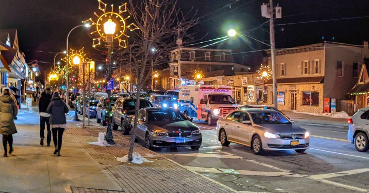 cars on street and people walking on sidewalk in lake george in winter