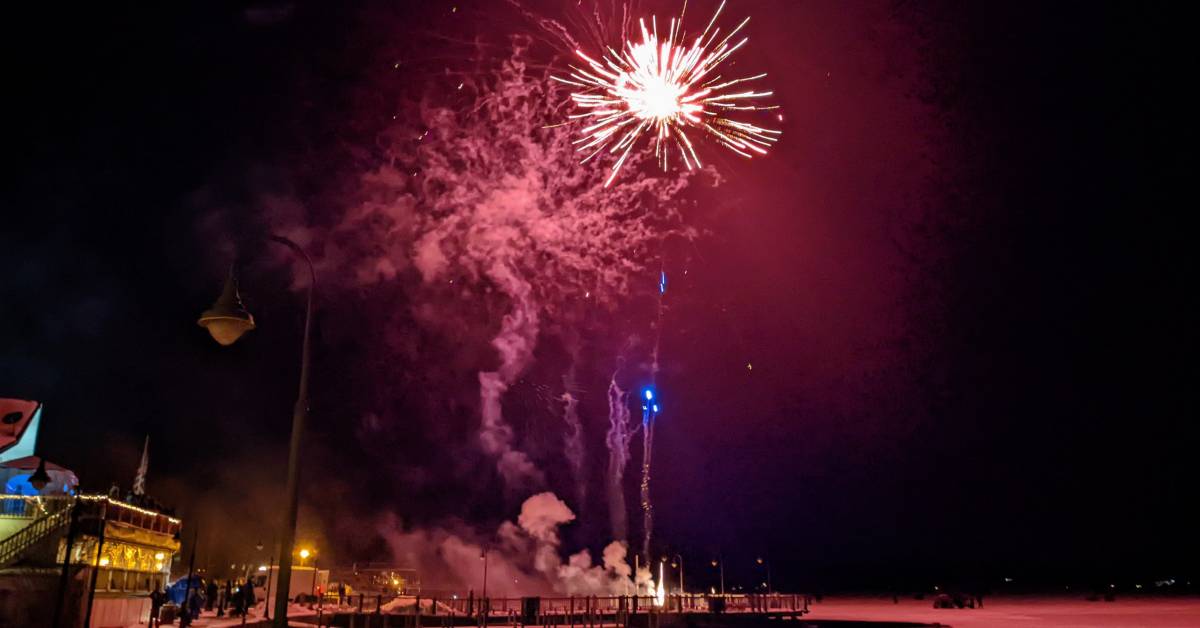 pink fireworks at night in winter over lake