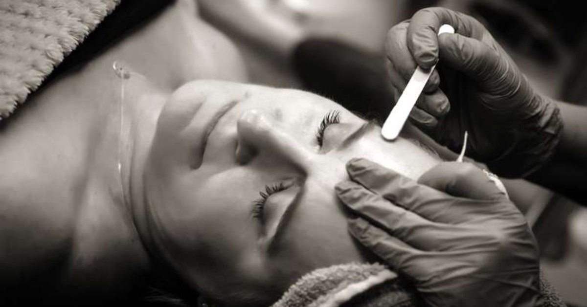 black and white photo of a woman's face being waxed