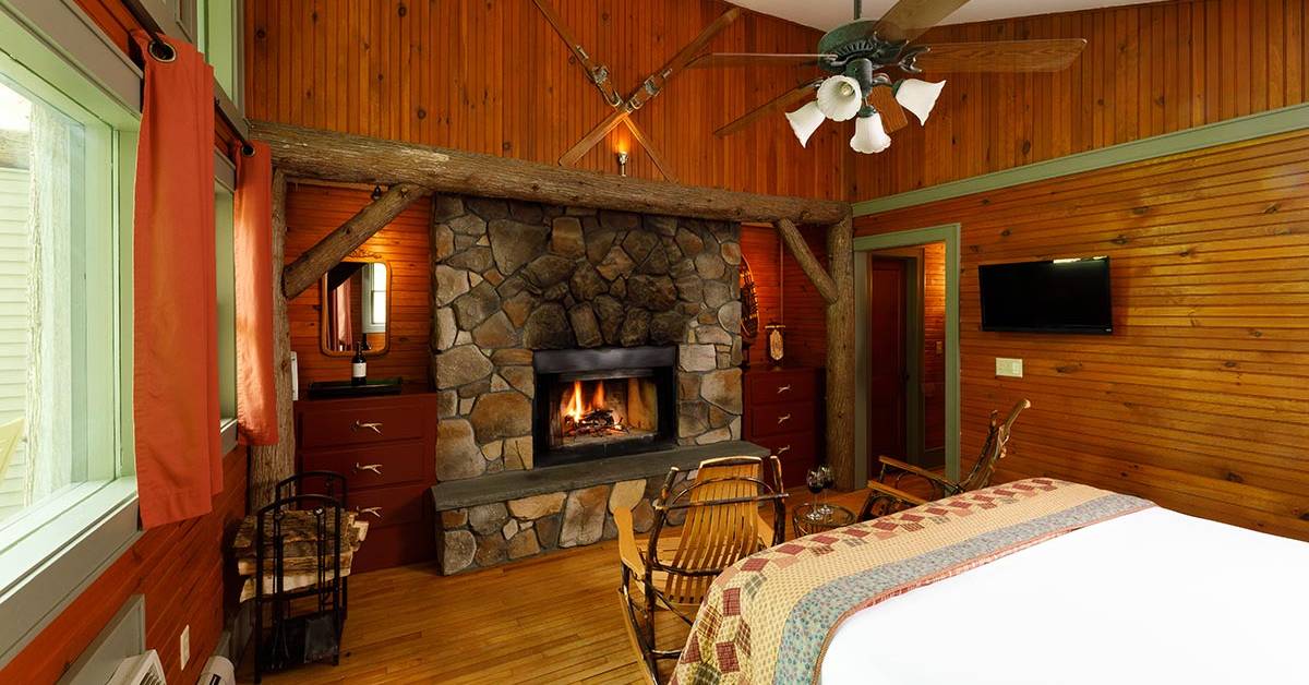 a rustic guest room with a stone fireplace and a bed