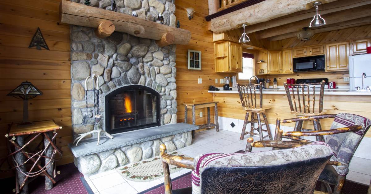 a rustic suite with a kitchen by a large stone fireplace