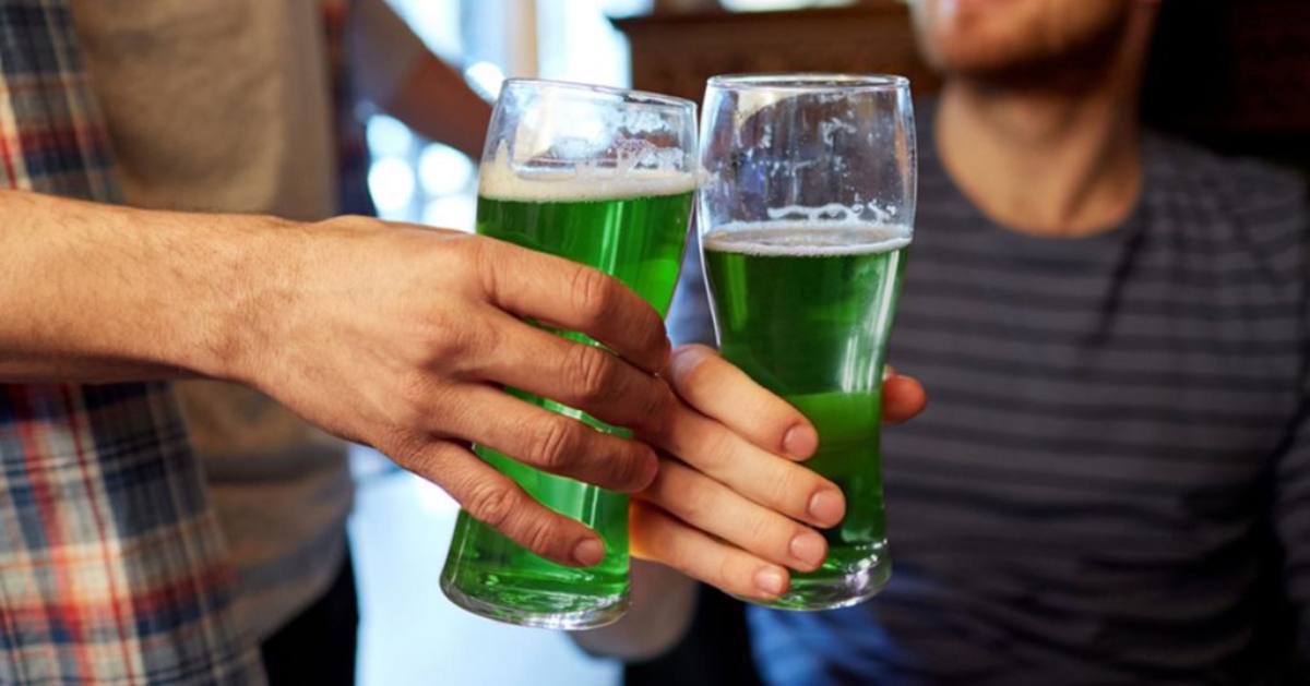 two people holding up glasses of festive green beer