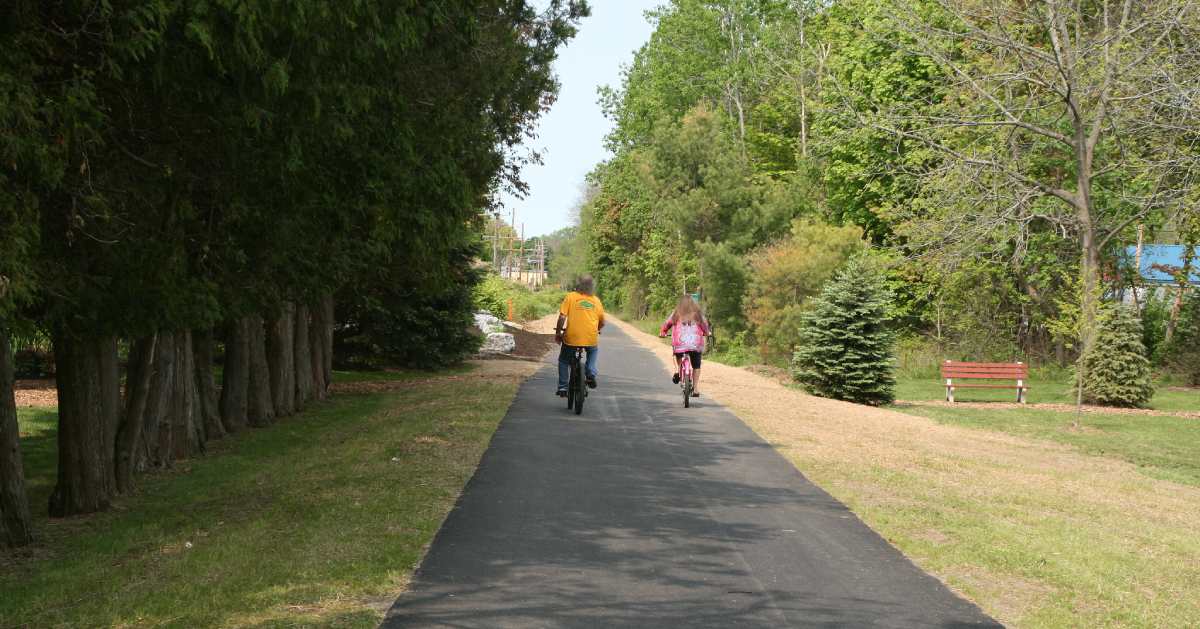 two people riding bikes down paved trail