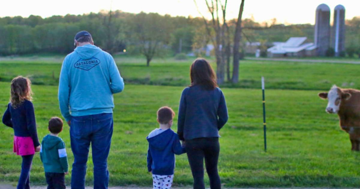 family on farmland with cow