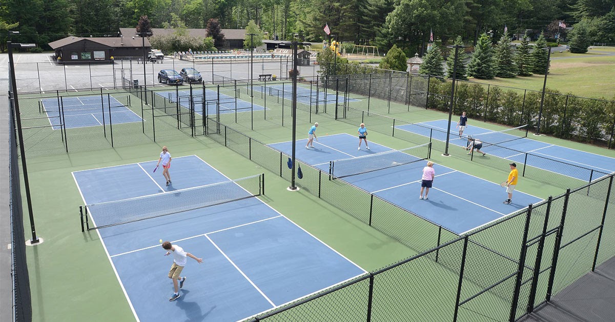 people playing pickleball in a fenced-in outdoor court