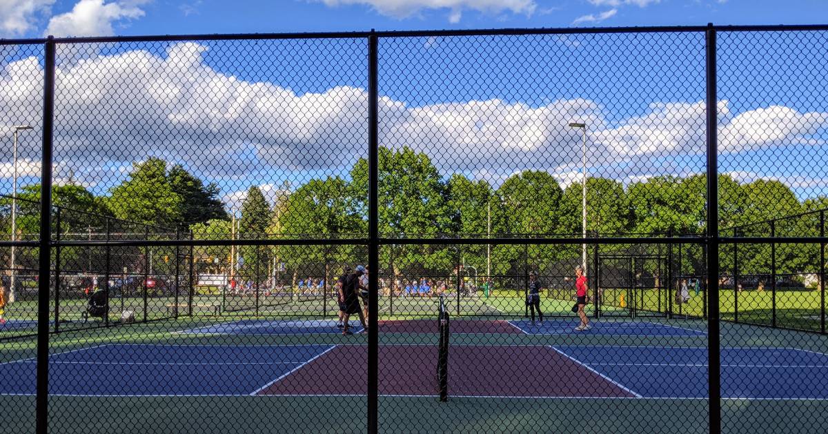 players on a pickleball court surrounded by a tall fence