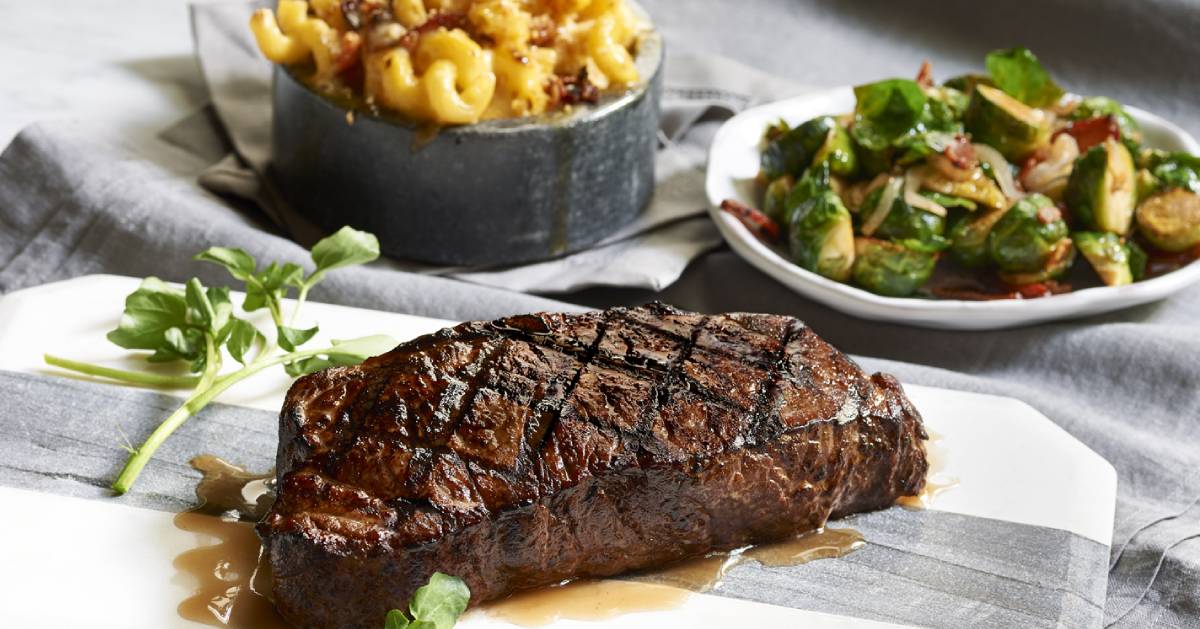 steak on a cutting board near food sides