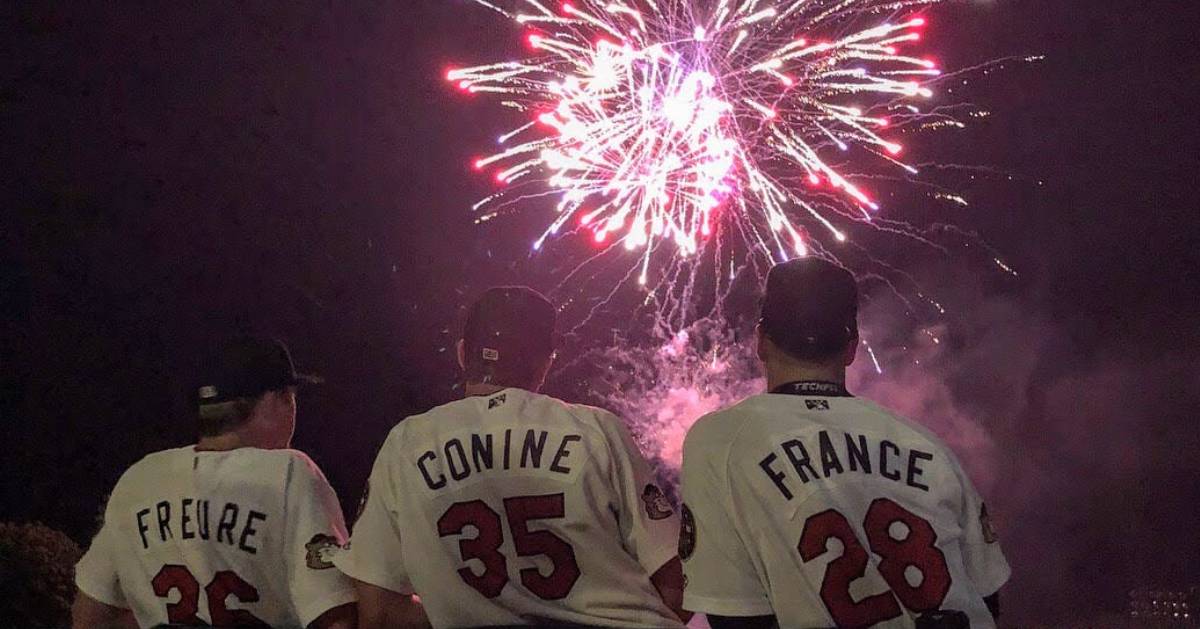 three baseball players watching fireworks