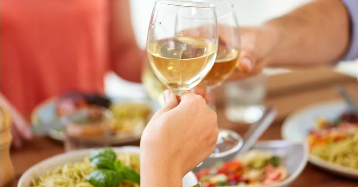 people with wine glasses and food at table