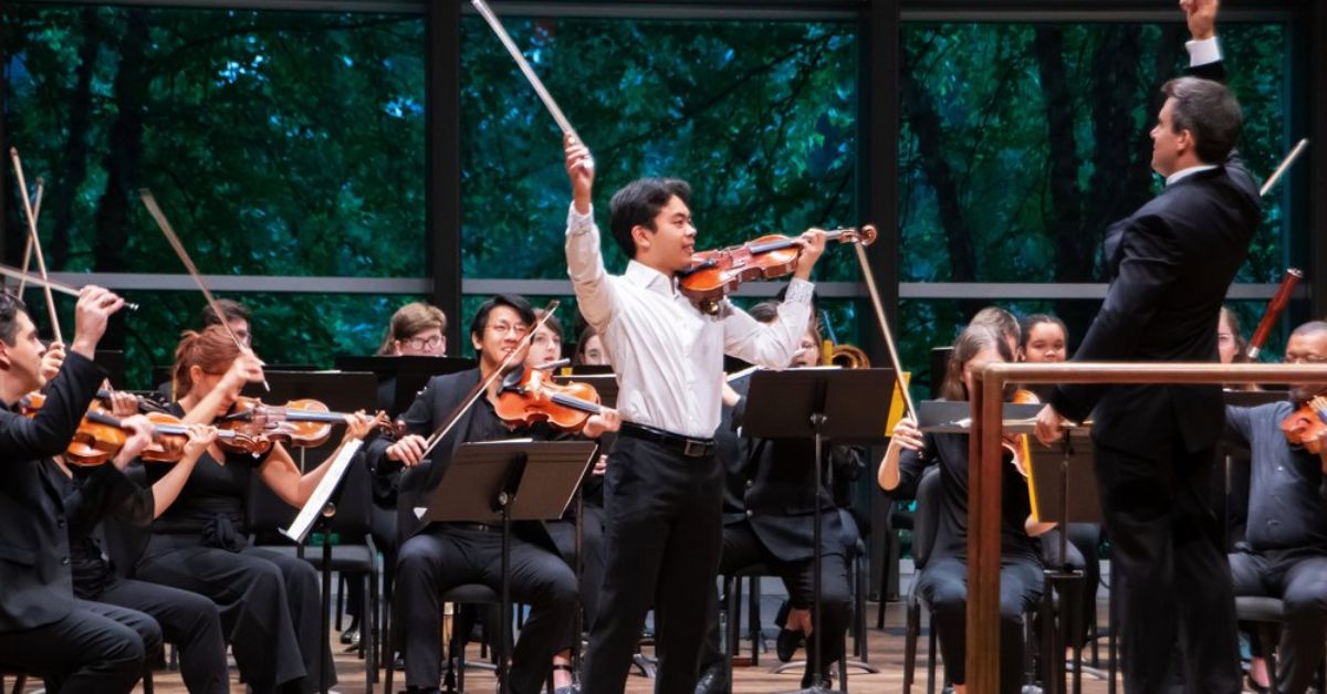 an ensemble performing on a stage with glass windows in the back