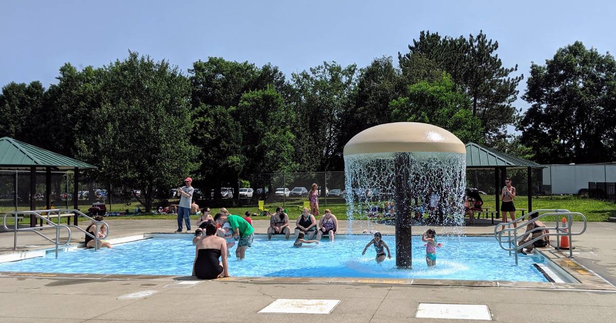 people in an outdoor pool with mushroom shaped water attraction