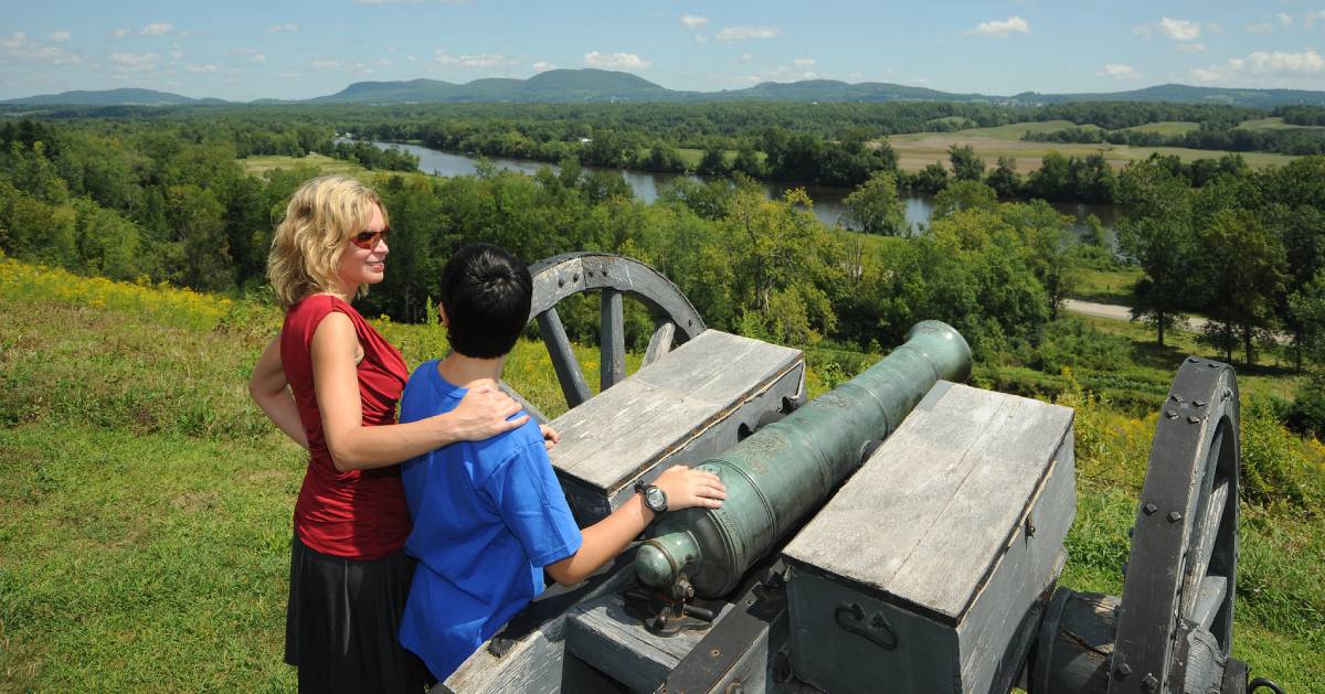 teen and woman by a cannon in a historical park