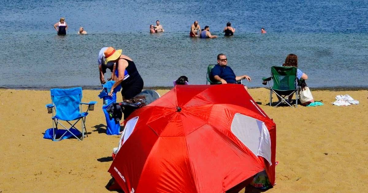 red umbrella on a beach, people in water