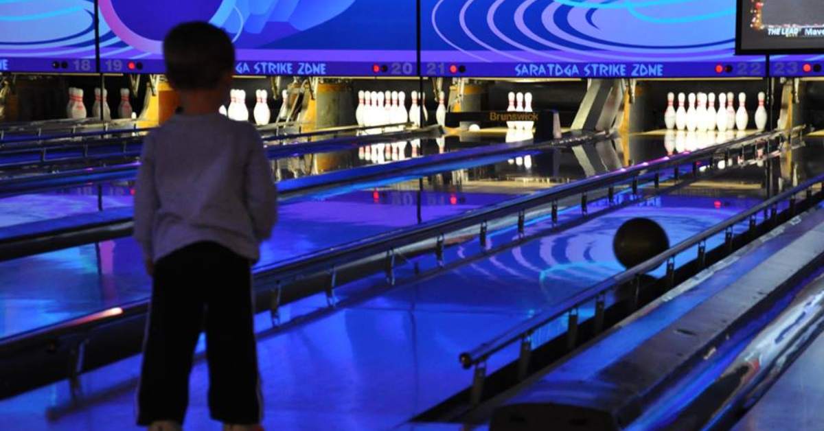 boy watching bowling ball roll down lane