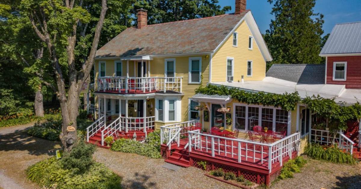 yellow farmhouse with red deck and white railing
